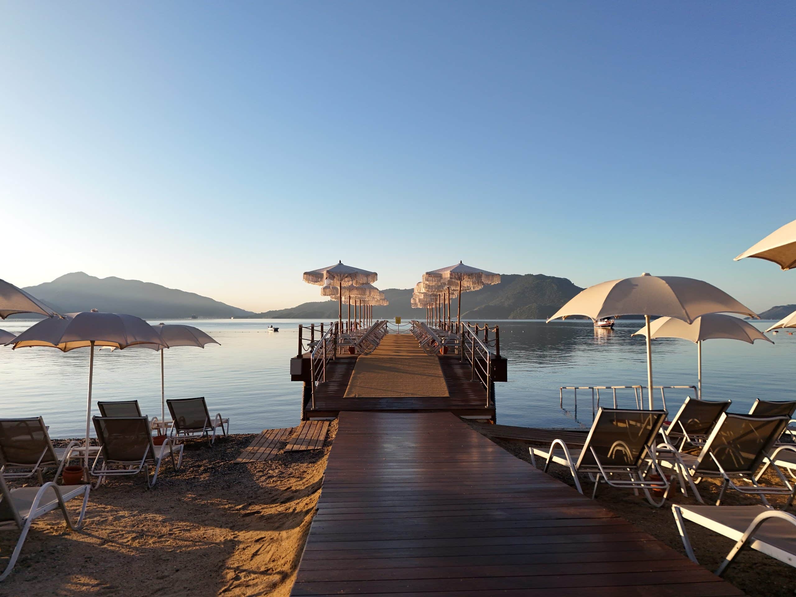 Emre Beach private pier with sunloungers and umbrellas at sunrise
